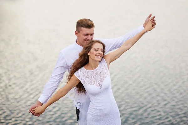 Vackra unga par promenader nära sjön på bröllopsdagen — Stockfoto