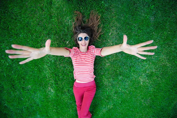 Frau mit Sonnenbrille liegt im Gras — Stockfoto
