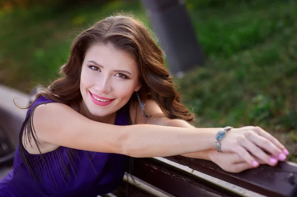 Young beautiful woman sitting on bench in park — Stock Photo, Image