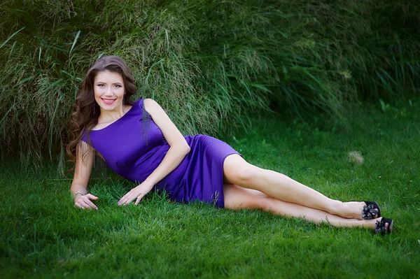 Beautiful woman lying on green grass in the park — Stock Photo, Image