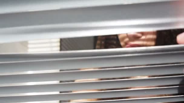 Femme regardant à travers les stores dans le bureau 