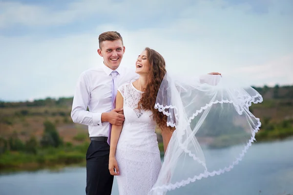 Loving bride and groom walking on a background of lake — Stock Photo, Image