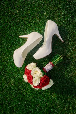 wedding bouquet and the brides white shoes on grass clipart
