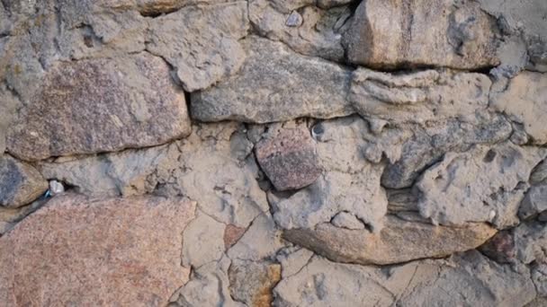 Текстура старых камней различных форм со швами. Закрыть потрепанную кладку. Каменная стена из неровных древних булыжников — стоковое видео