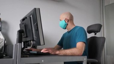 Koruyucu maske takan bir adam evde çalışıyor. Koronavirüs için koruyucu maske takarak karantina. Evden çalışmak