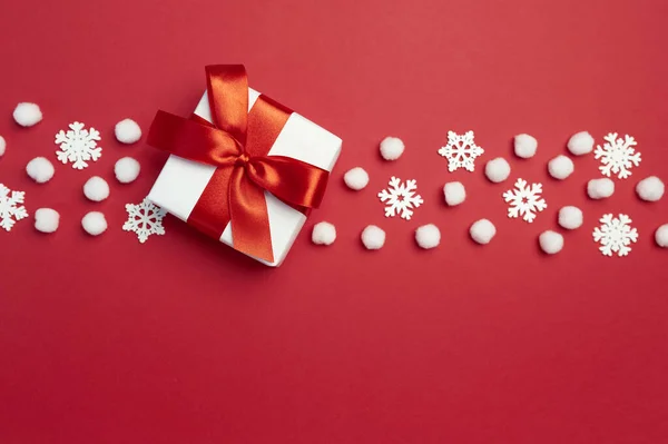 Natal cartão de saudação feriado com caixa de presente com fita vermelha e flocos de neve no backgroun vermelho. Natal cartão postal de férias com lugar para o seu texto. Feliz Ano Novo — Fotografia de Stock