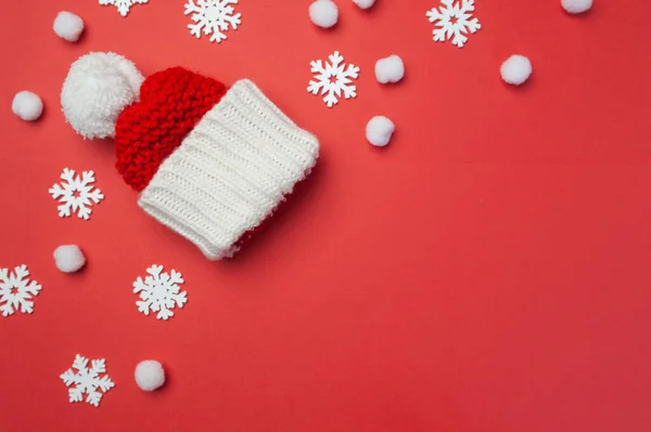 Tarjeta de felicitación navideña con sombrero rojo y copos de nieve sobre fondo rojo. Tarjeta postal navideña con lugar para su texto. Feliz Año Nuevo —  Fotos de Stock