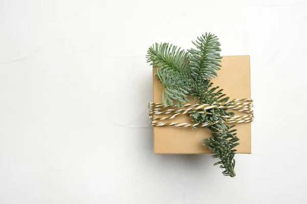 Composición navideña con ramas de abeto verde y caja de regalo kraft sobre fondo de madera blanca con copyspace —  Fotos de Stock