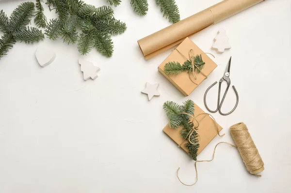 Weihnachtskomposition mit grünen Tannenzweigen und Kraftpapier-Geschenkschachteln und -scheren auf weißem Hintergrund, Draufsicht mit Copyspace — Stockfoto