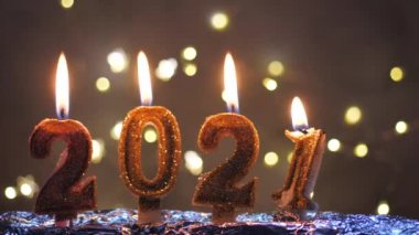 Mutlu yıllar 2021 kutlamaları. Noel arkaplanında 2021 numara şeklinde altın yanan mumlar.