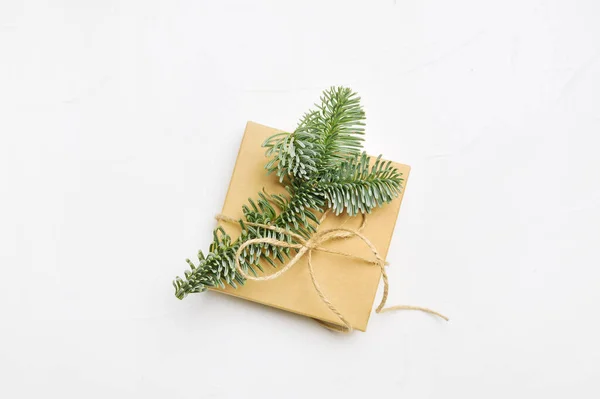 Kerst compositie met groene sparren takken en kraft geschenkdoos op witte houten achtergrond met copyspace — Stockfoto