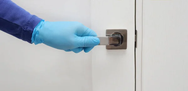 Männerhand in blauen Schutzhandschuhen öffnet oder schließt die Tür. Antibakterielle Prophylaxe in Zeiten von Viren und Infektionen. Gesundheits- und Schutzkonzept — Stockfoto