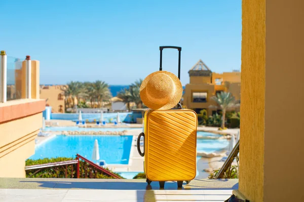 Travel, summer holidays and vacation concept yellow suitcase with hat on background of hotel pool area in Egypt — Stock Photo, Image