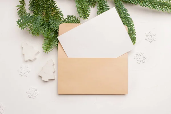 Weihnachtsgrußkarte mit Umschlag auf weißem Holzgrund mit Tannenzweigen und frohem neuen Jahr. Kopierraum von oben — Stockfoto