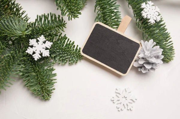 Composition de Noël avec branches de sapin vert, cône et décorations en bois blanc de flocons de neige sur fond en bois blanc, avec copyspace — Photo