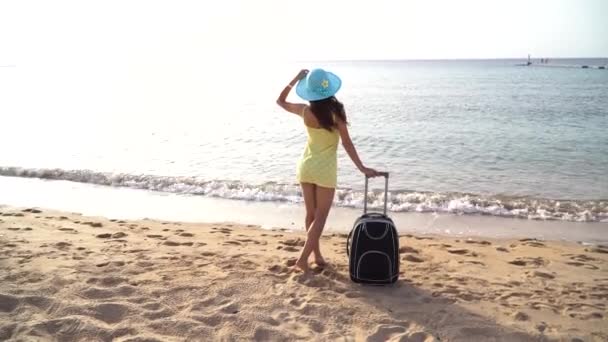 Mulher bonita em um chapéu com mala contra o mar durante as férias de viagem de verão. mulher feliz olhando para o mar. Filmagem de movimento de vídeo Full HD — Vídeo de Stock