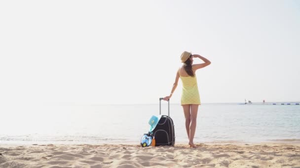 夏の旅行休暇中に海に対するスーツケース付きの帽子の美しい女性。幸せな女性は海を見て。フルHDビデオ映画 — ストック動画