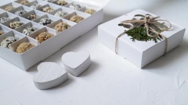 Paper box with chocolates and two wooden white hearts on table. Video footage HD — Stock Video