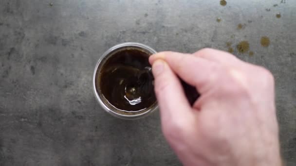 Vista dall'alto di Persona mano sterzo caffè in una tazza con cucchiaio. Mattina di colazione di una tazza di caffè nero caldo su sfondo di legno. scena del filmato 4k. casa facendo il caffè — Video Stock