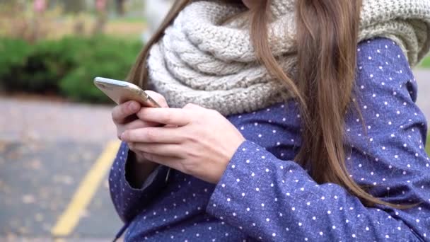 Mujer feliz escribiendo por teléfono móvil al aire libre. Primer plano chica alegre caminando con teléfono inteligente en el fondo urbano. señora sosteniendo el teléfono celular en las manos fuera — Vídeo de stock