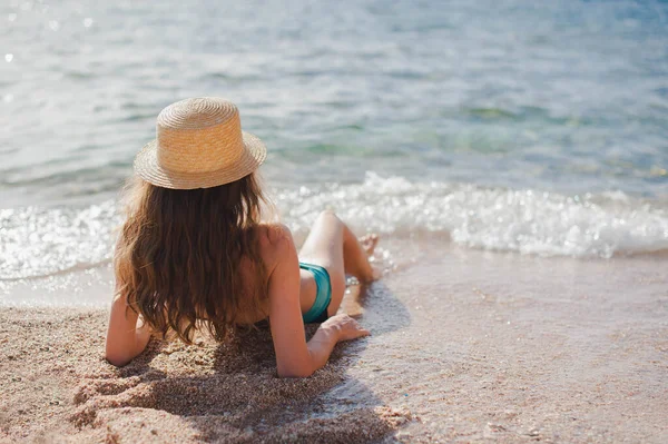 Jeune femme maigre en chapeau couché sur la plage sur le sable jaune près de la vague de la mer. Vue de dessus belle fille en bikini sur la plage. Vacances d'été concept Voyage — Photo
