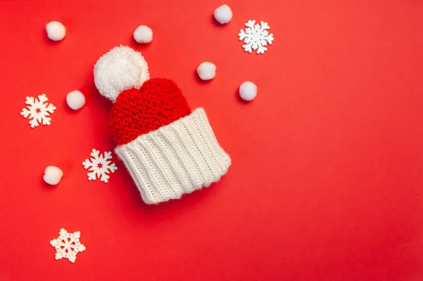 Tarjeta de felicitación navideña con sombrero rojo y copos de nieve sobre fondo rojo. Tarjeta postal navideña con lugar para su texto. Feliz Año Nuevo invierno — Foto de Stock