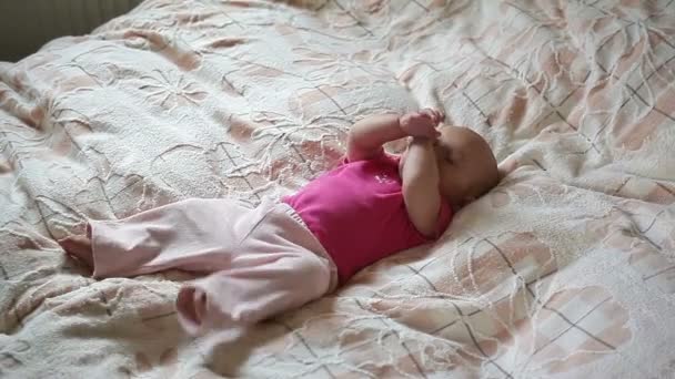 Маленька дитина лежить на ліжку і сміється — стокове відео