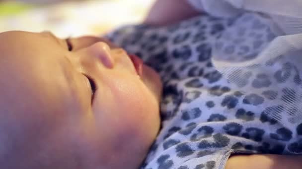 Babymeisje in een mooie jurk liggend op het bed — Stockvideo