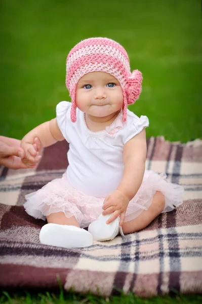 Baby girl in the park in a pink knitted hat — Stock Photo, Image