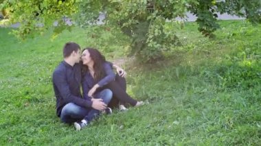 birlikte parkta çimlerde oturan kadın ve erkek