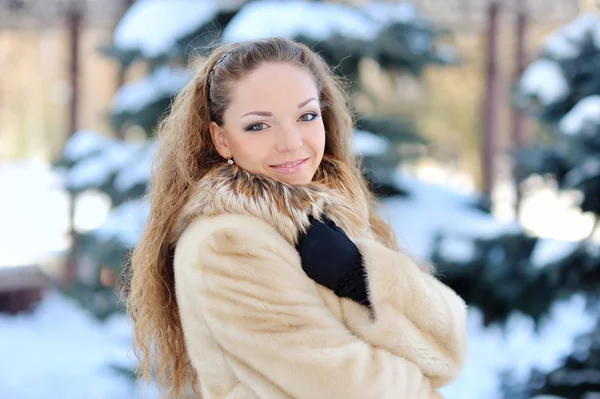 En tjej som bär varma vinterkläder och hatt blåser snö i winte — Stockfoto