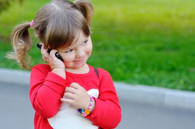 küçük kız telefonla konuşuyor. 