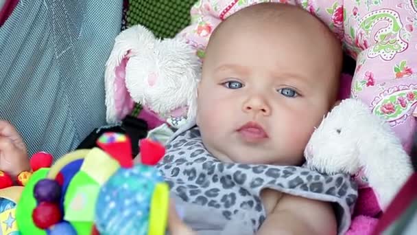 Mooie babymeisje zit met een stuk speelgoed — Stockvideo
