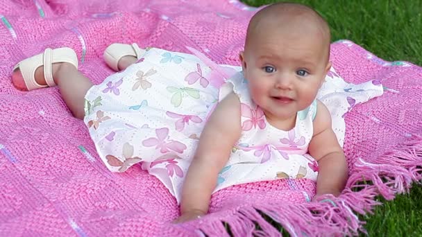 Gelukkig lachend vrolijke babymeisje op roze deken in park — Stockvideo