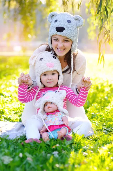 Madre e hija en sombreros de punto Osos, con una muñeca — Foto de Stock