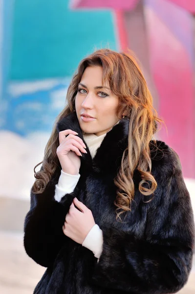 Girl in a black winter coat on a bright background — Stock Photo, Image