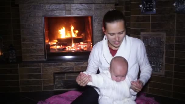 Mãe sentada com seu bebê perto da lareira no Natal — Vídeo de Stock