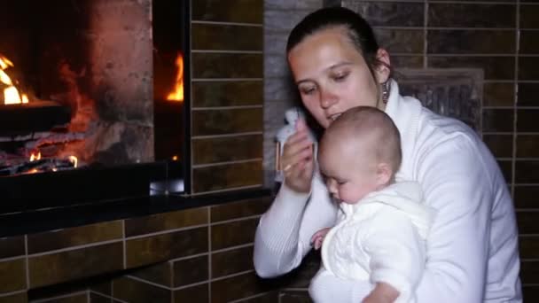 Mutter sitzt an Weihnachten mit ihrem Baby am Kamin — Stockvideo