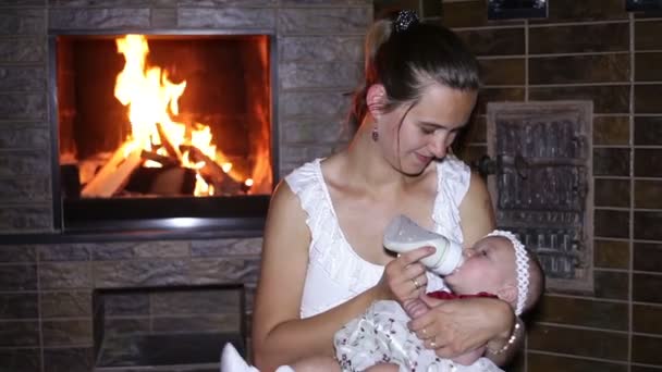 Mother feeds her baby near the fireplace — Stock Video