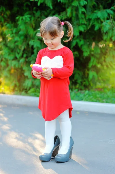 Красивая маленькая девочка в парке в туфлях моей матери — стоковое фото