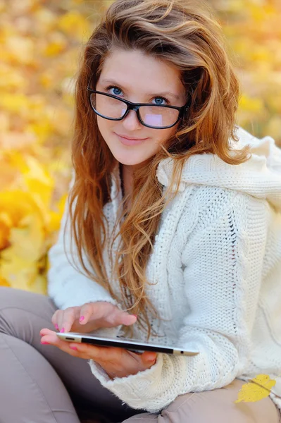 Sonbahar bir parkta elinde bir tablet ile Kız bardaklarda — Stok fotoğraf