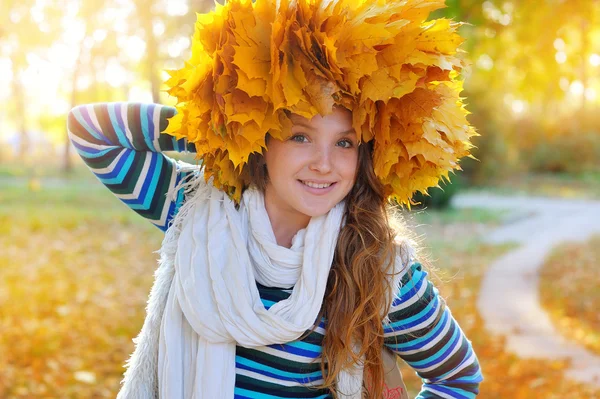 Young pretty woman in the autumn park makes a wreath of leaves — Stock Photo, Image