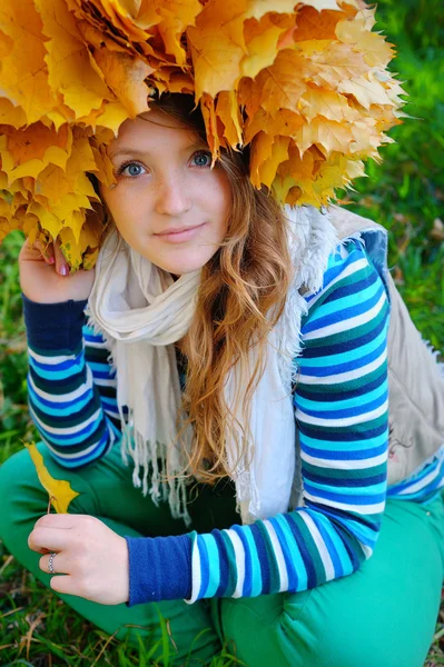 Junge hübsche Frau im Herbstpark macht einen Laubkranz — Stockfoto
