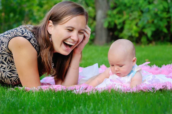 Happy mother and baby laying on meadow — Stock Photo, Image