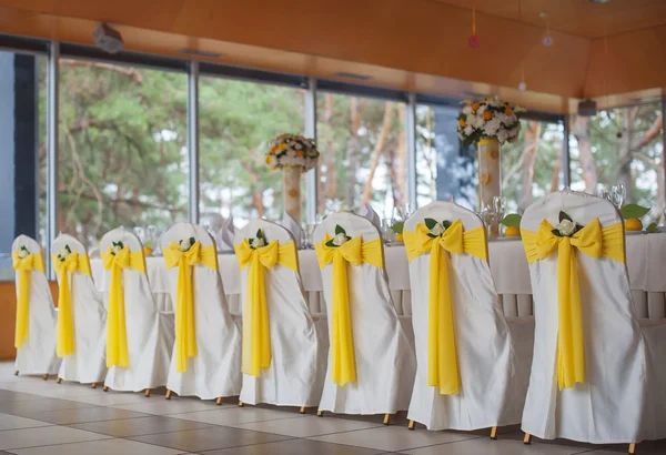 Chaises de mariage en rangée décorées avec un ruban de couleur dorée . — Photo