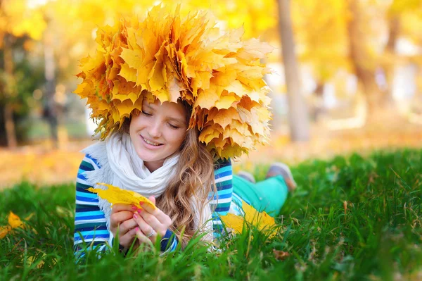 Young woman sitting on gold autumn leaves, top view — Stock Photo, Image
