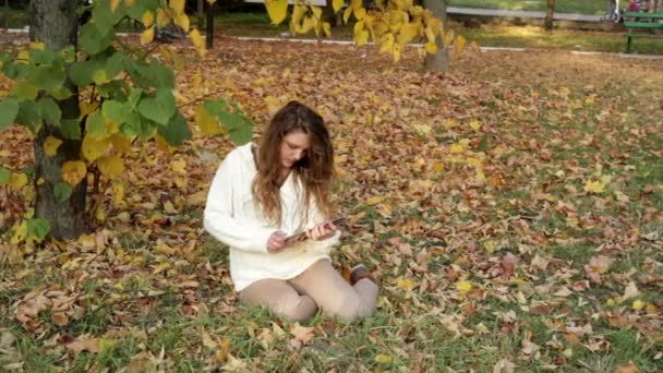 秋の風景にタブレットで微笑んでいる女の子 — ストック動画