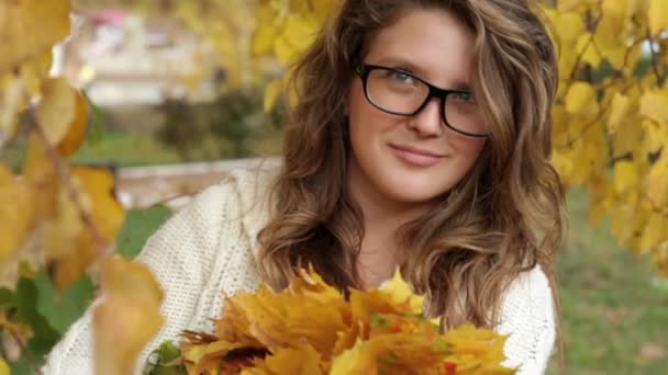 Fille dans des lunettes dans le parc d'automne sur les feuilles — Video