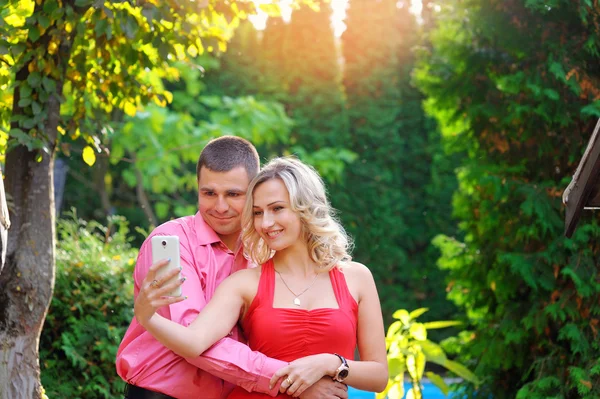 Affectionate young couple taking pictures using a smart phone at — Stock Photo, Image