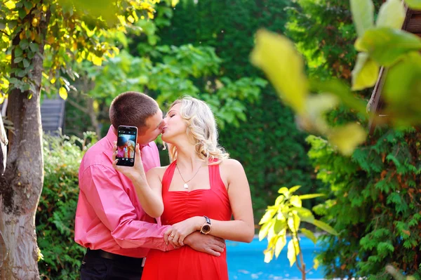 Happy man and woman kiss and make self on phone — Stock Photo, Image